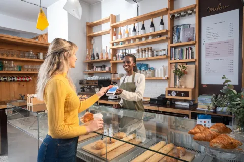 Medewerker van een bakkerij met koffiebar houdt een myPOS Ultra pinapparaat voor een klant