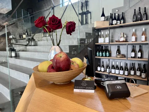 myPOS Carbon pinapparaat op de toonbank van een wijnhandel tussen fruit en flessen wijn