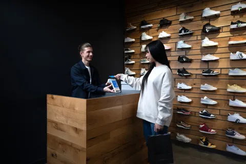 Klant houdt haar bankpas bij een myPOS Ultra pinapparaat aan de toonbank van een schoenenwinkel