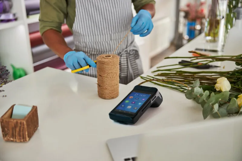myPOS Carbon pinapparaat op de werkbank van een bloemist tussen bloemen en touw